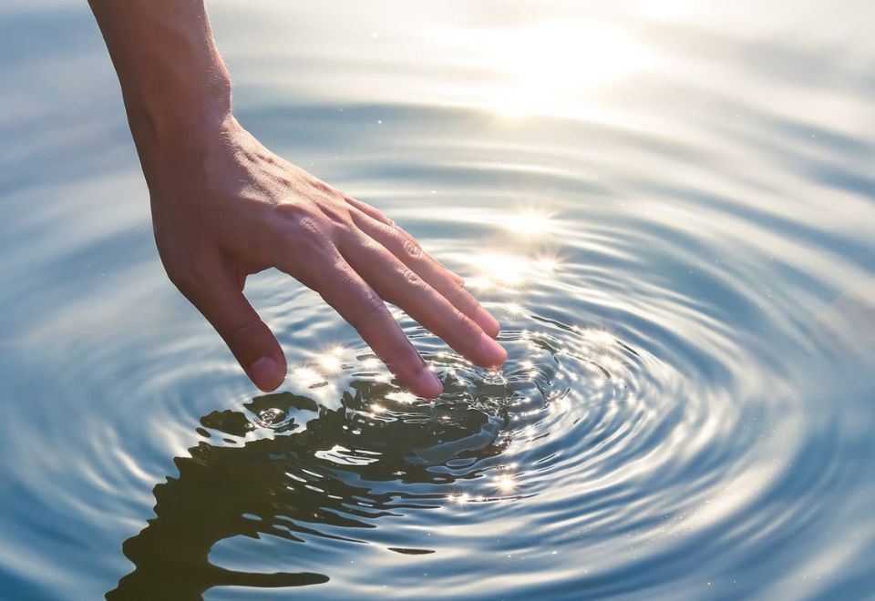 A hand touching still water